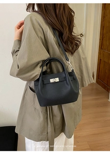 Detail of black pebbled leather bucket bag with silver turn-lock and leather strap closure