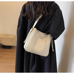 Détail du sac hobo blanc cassé avec poche avant et surpiqûres sur un mannequin