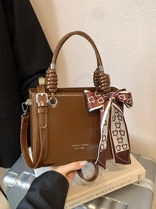 Glossy brown vintage shoulder bag with bear scarf accent on silver suitcase