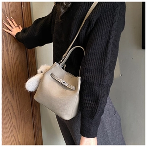Detail of grey lychee leather bucket bag with turn-lock closure and plush charm