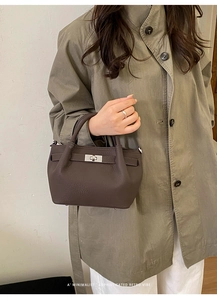 Detail of dark brown lychee leather bucket bag with silver twist lock on khaki trench coat
