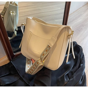 Détail du sac seau crème avec bandoulière jacquard géométrique et boucles en bronze