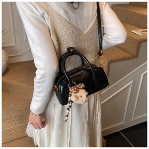 Photo lifestyle d'un sac cylindrique noir avec pendentif ours sur des escaliers