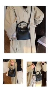Detail of black pebbled leather bucket bag featuring silver belt buckle and plush charm