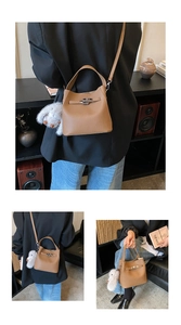 Detailed view of a brown pebbled leather bucket bag with a metal twist lock and rabbit charm