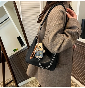 Détail du sac cabas en cuir noir avec chaîne argentée et pendentif peluche ours mignon