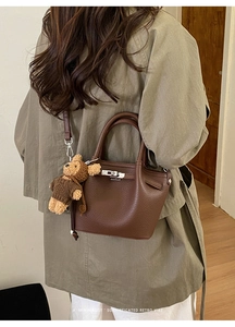 Close-up of deep brown litchi pattern leather bag with bear charm and silver buckle detail