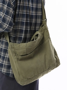 Japanese army green washed canvas messenger bag worn cross-body over a plaid shirt