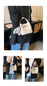 Detailed view of cream lychee leather bucket bag with metal buckle and plush rabbit charm