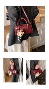 Détail du sac Boston bordeaux en similicuir avec texture cirée rétro et breloque