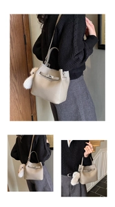 Detail of grey lychee leather bucket bag with silver turn-lock and plush bunny charm