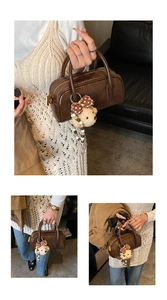 Détail d'un sac à main marron en cuir verni avec pendentif ourson et fermeture dorée