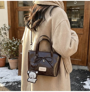 Close-up of vintage brown leather bucket bag with bear charm and heart pendant detail