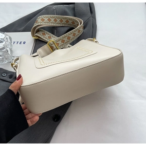 Détail du sac seau en cuir crème avec bandoulière en jacquard et coutures de base solides