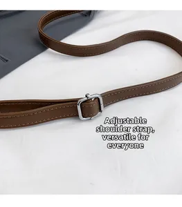 Détail d'une bandoulière réglable en similicuir marron avec boucle en métal argenté