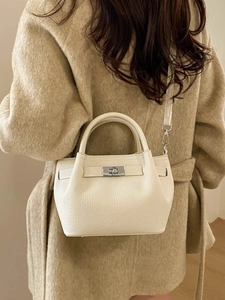 Ivory leather bucket bag with silver turn-lock clasp shown on model in beige coat