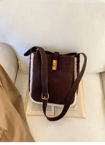 Detail der dunkelbraunen Wildleder-Beuteltasche mit weißem Pelzbesatz und goldener Schließe
