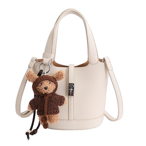 Borsa a secchiello beige in pelle con motivo litchi e ciondolo a forma di orsetto