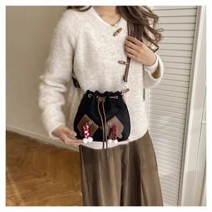 Détail d'un sac seau noir avec des mini breloques chaussettes et des poches en cuir brun