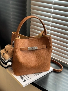 Brown litchi grain leather bucket bag with dog plush pendant and silver twist lock