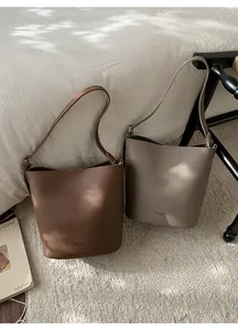 Detail of high-capacity bucket bags in lychee leather with branded base engraving
