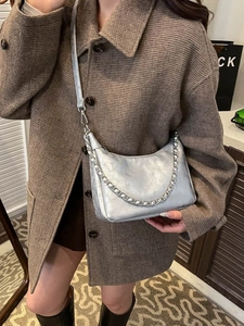 Sac hobo métallisé argenté avec chaîne porté sur un manteau en laine à carreaux