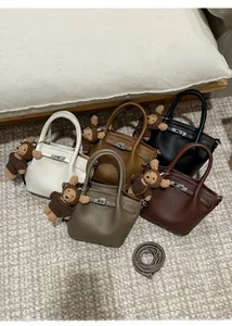 Detailed top view of lychee leather bucket bags in five colors with plush bear charm