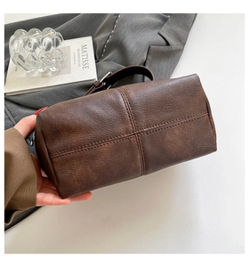 Detail of vintage brown leather horn bag with cross stitching and silver metal buckle