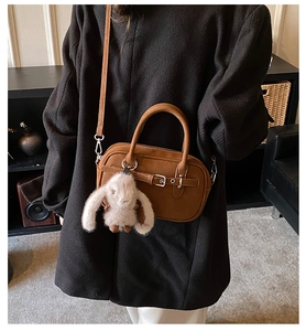 Close-up of brown vintage square handbag featuring a cute plush bunny charm and strap
