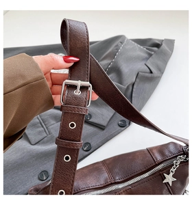 Detail of dark brown vintage shoulder bag strap with silver buckle and star charm