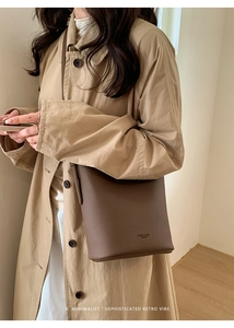 Close-up of deep brown lychee grain leather texture and brand logo on a tote bag