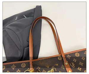 Detail showing the brown monogram tote bag with light brown leather strap and gold rivets