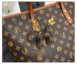 Detailed macro view of monogram tote bag with gold kangaroo logo and dog charm detail