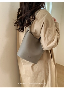 Detail of grey bucket bag showing litchi texture and MICKY & BAGS FASHION embossed logo