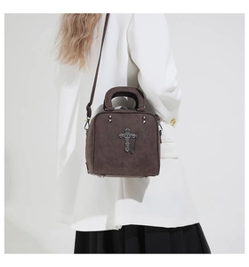 Detail of dark brown leather box bag with gothic metal cross pendant and thin chain