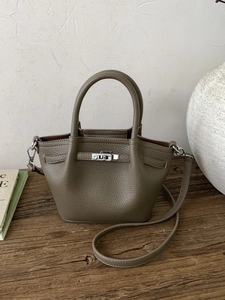 Taupe pebbled leather tote bag with top handles and twist-lock on a wooden desk