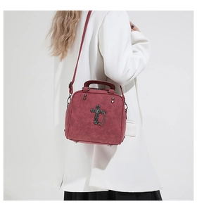 Burgundy gothic handbag with metal cross and chain shown on model in studio