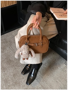 Detailed view of a brown square tote bag with decorative buckle and plush rabbit charm