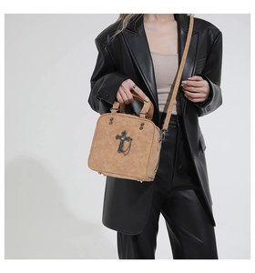 Retro camel suede pillow bag with cross charm and studs worn by model in leather suit