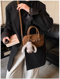 Brown vintage square handbag with rabbit plush charm and adjustable strap shown on model