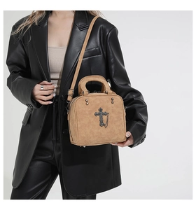 Detail of khaki suede crossbody bag featuring retro black cross and rivet accents