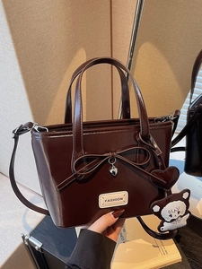 Glossy dark brown bucket bag with a bow decoration and cute bear charm in retro style