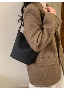 Close-up of black lychee grain leather bucket bag styled with a tweed blazer outfit