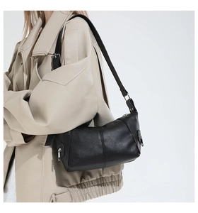 Detail of black dumpling shoulder bag with lychee texture and silver zipper accents