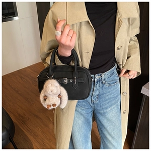 Detail of black matte leather handbag with strap buckle and cute plush rabbit charm