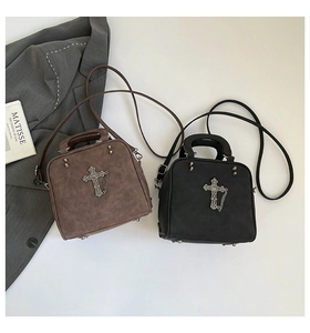 Detail of gothic style faux leather tote bag with silver cross and metal chain accents