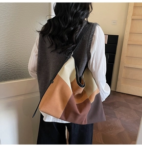Rear view of model wearing a large earth-toned canvas patchwork tote with leather strap