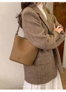 Detail view of large capacity brown pebbled leather bucket bag with brand logo