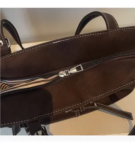 Gros plan sur la fermeture éclair argentée et coutures contrastées du sac cabas marron