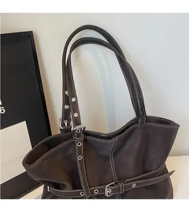 Détail d'un sac cabas en cuir marron foncé avec coutures contrastées et sangles à boucles